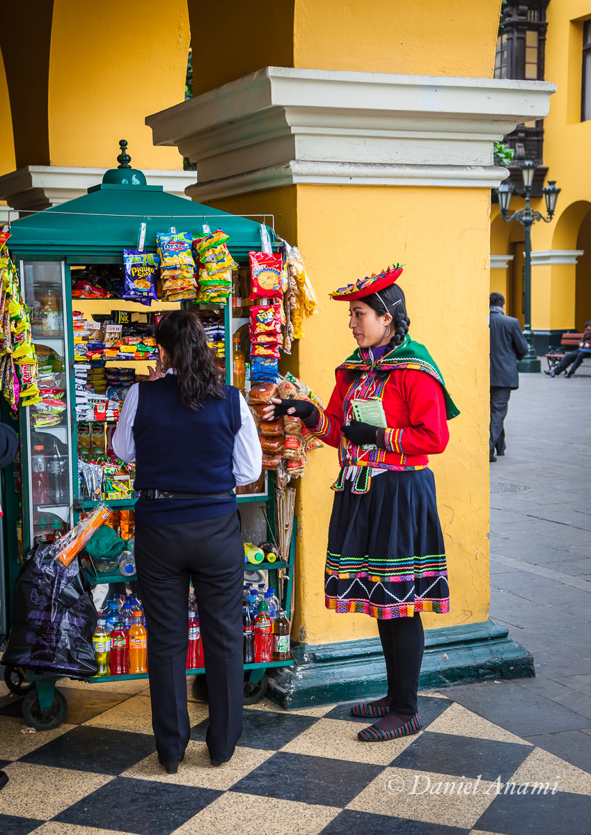 Uma moçoila vestida com roupas tradicionais compra seu lanchinho embaixo dos arcos do Palacio de la Unión, Lima, 13/08/13. Foto Daniel Anami.